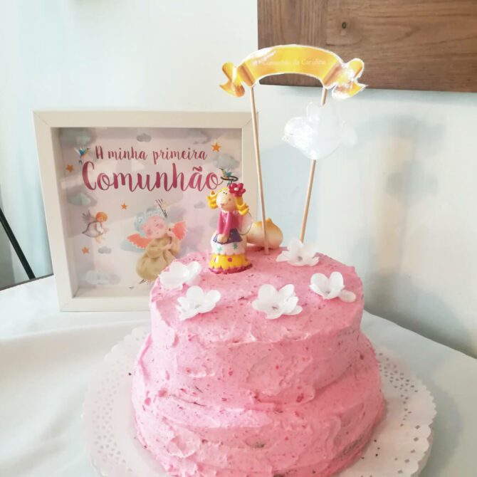 presente primeira comunhão a decorar uma mesa com bolo cor-de-rosa